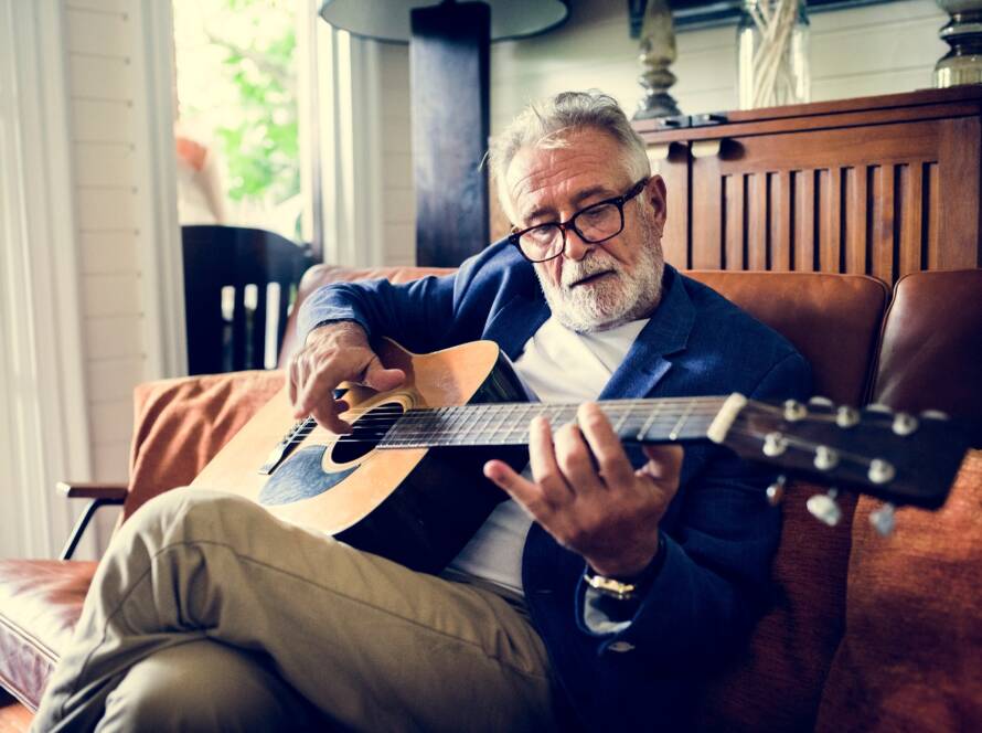 An elderly man is playing guitar