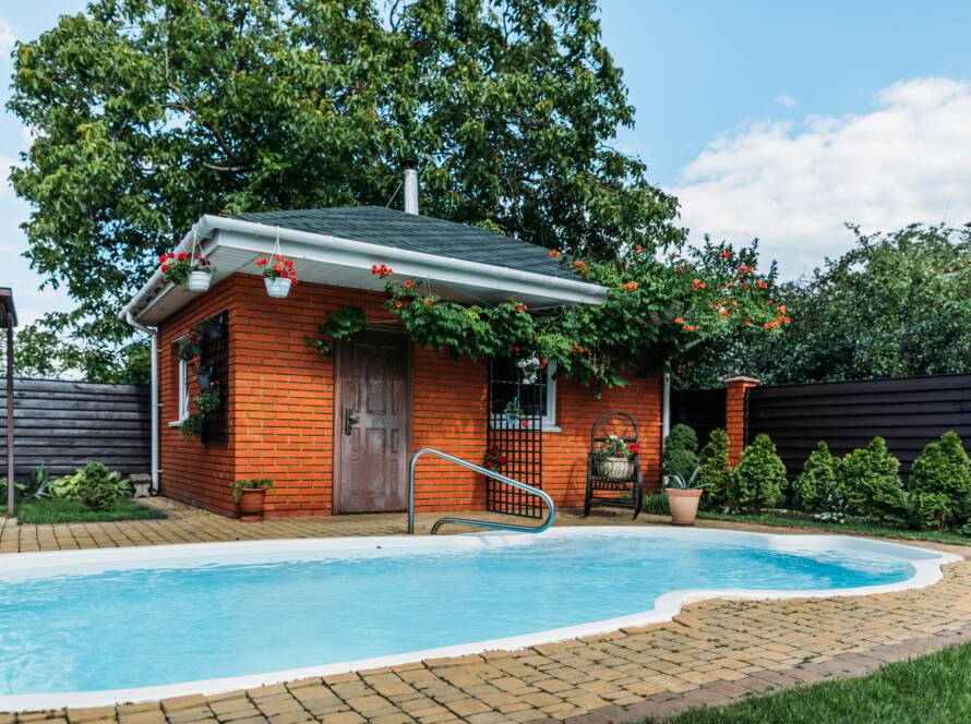 wooden country house with swimming pool near by, trees and cloudy sky